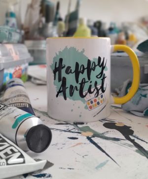 Happy Artist Mug in yellow in the art studio